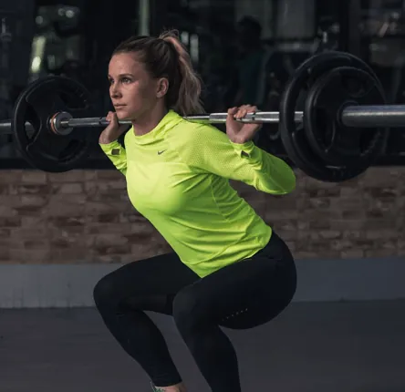 Woman squatting with barbell — strength training tips for women beginners
